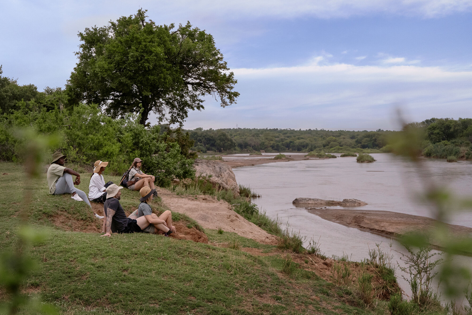Guests overlooking the river at dusk in the African wilderness
