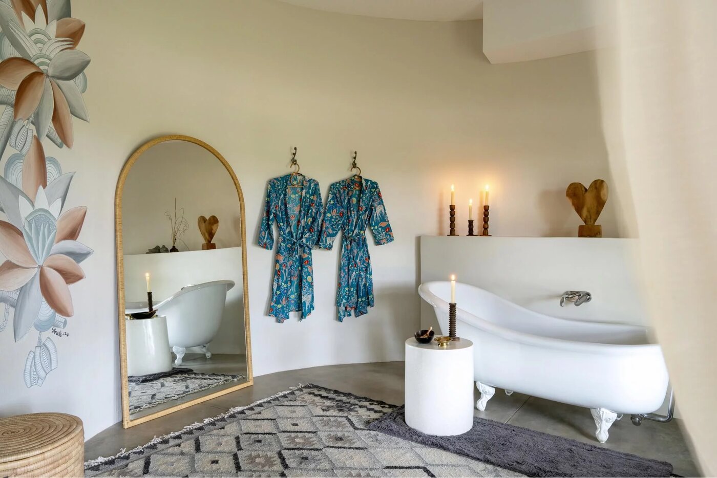 Luxury clawfoot tub with botanical wall mural, silk robes, and candles